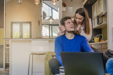 Happy couple doing business together working at small office at home, Portrait of a cheerful woman hugging man from behind