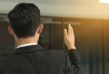 back of pensive smart businessman speech, standing back and pointing finger, blurred