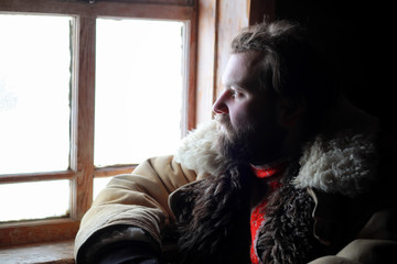 man in traditional winter costume of peasant medieval age in russian house