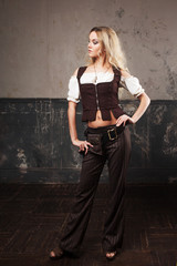 Portrait of a beautiful steampunk woman in a pant suit with vest, over grunge background.