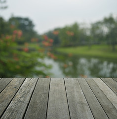 Empty old wood floor with blur of red flower and tree in public park