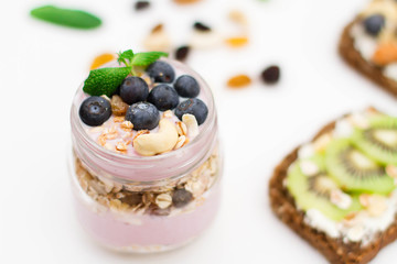 Breakfast. Muesli, nuts and berries. preparation. Granola with fresh berries in jar on stone background. Healthy food and Clean Eating concept