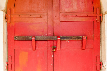 Close-up double lock system, metal padlock and wooden log on traditional antique red wooden door.