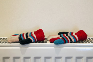 Childs knitted gloves drying on heating radiator after winter day outside