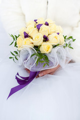 букет из роз и фиолетовых лент в руках невесты