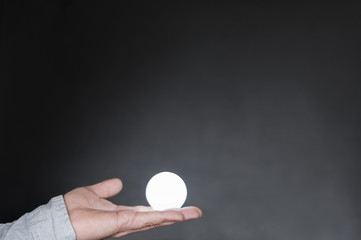 Hand mit Gluehbirne /Hand mit Gluehbirne vor dunklem Hintergrund mit Textfreiraum.