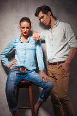 woman sitting on stool while boyfriend leans on her shoulder