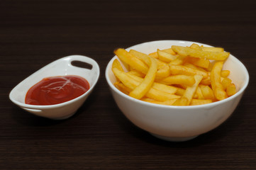 Fresh fried french fries with ketchup on wooden background. Fresh potato fries.