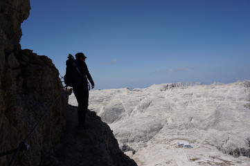 Wanderin auf Klettersteig unterwegs im Hintergrund bleiches Hochplateau auf Sella Gruppe 