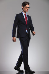 young business man wearing glasses is walking