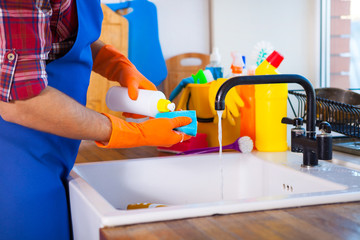 Man makes cleaning the kitchen. Young man washes the dishes. Cleaning concept.