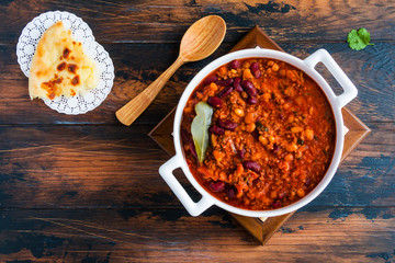 Traditional Polish cuisine, stewed Breton beans  with minced beef, bacon, mashed tomatoes, onion, garlic, paprika, bay leaves and spices. White casserole on wooden rustic table, top view.