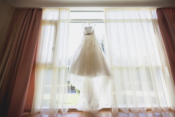 Beautiful wedding dress hanging in the bride's room