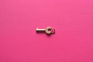 Golden key on a pink background.