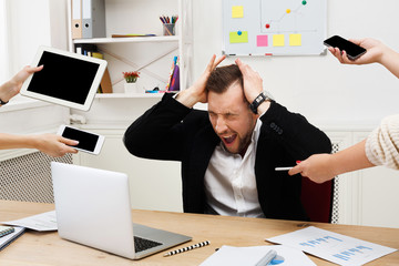 Young stressed overworked businessman in modern office