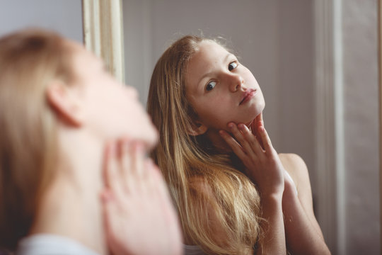 Teenage girl checking her face and body in the mirror