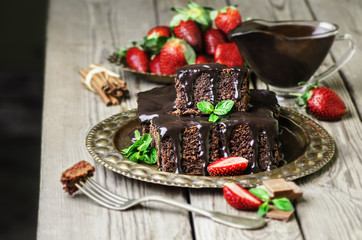 Delicious Chocolate cake with fresh strawberries on rustic wooden background.