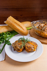 Rissole of pork served on a white plate with white wheat bread and herbs - dill, green onion, parsley around the plate.