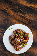 Crispy sesame chicken wings with a sticky sweet Asian sauce and white boiled rice on a plate on wooden table, top view. - 137769025