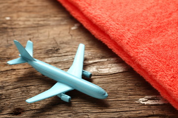 The blue color jet plane toy model put beside the towel on wooden floor surface represent the tourism and travel industry concept related idea.