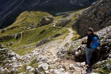 Wanderin alleine unterwegs mit Rucksack und Stecken in den Bergen in felsiger Gebirgslandschaft