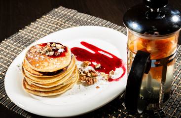Breakfast with sweet pancakes topped blueberry jam, teapot with fruit tea