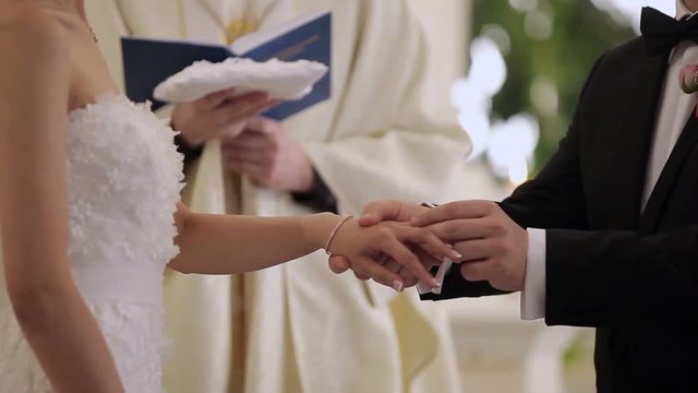Groom puts a ring to brides hand at wedding ceremony