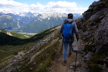 Fototapeta na wymiar Wanderin alleine unterwegs mit Rucksack und Stecken in den Bergen / Aussicht auf Dolomiten Gipfel