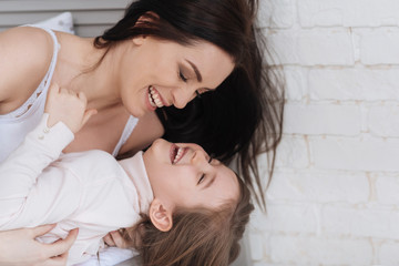 Cheerful laughing mother holding her daughter