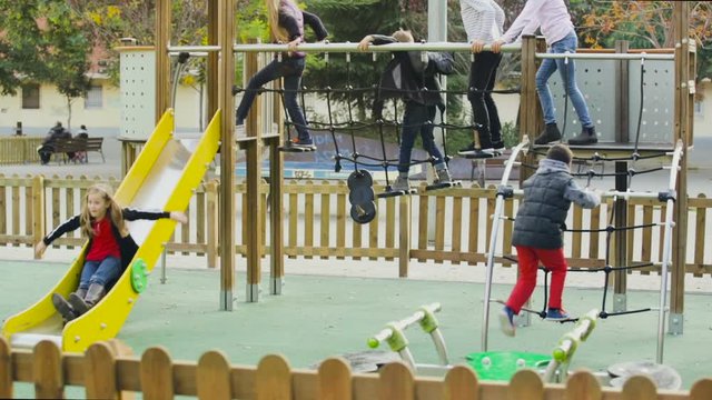 
cheerful boy and girls in elementary school age having fun on slide 