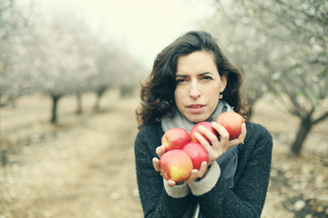 Outdoor portrait of 40 years old woman holding red apples