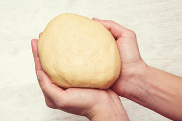 Hands holding shortcrust pastry in the kitchen. Homemade pastries.