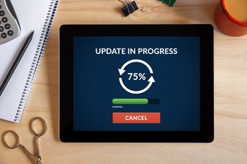 Naklejka premium Update concept on tablet screen with office objects on wooden desk. All screen content is designed by me. View from above.