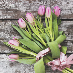 Bouquet of pink tulips on a shabby wooden table.