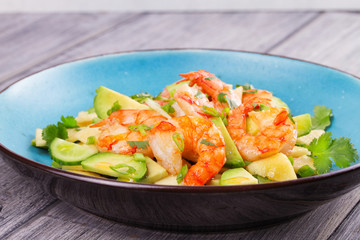 Shrimp, Avocado, Apple and Onion Salad. Grilled prawns on blue plate.