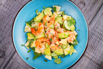 Shrimp, Avocado, Apple and Onion Salad. Grilled prawns on blue plate. View from above, top studio shot