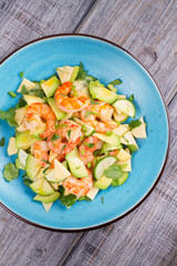 Shrimp, Avocado, Apple and Onion Salad. Grilled prawns on blue plate. View from above, top studio shot
