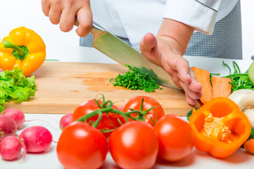fresh raw vegetables for salad and chef hands with a knife close up