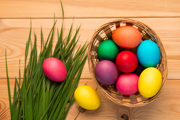 basket with colorful Easter eggs and lush grass top view