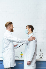 side view of scientists in white coats discussing experiment results in lab