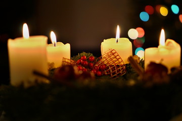 Detail of burning candles with background made of colorful bokeh lights placed on the Christmas tree as a symbol of peaceful and serene holiday time 