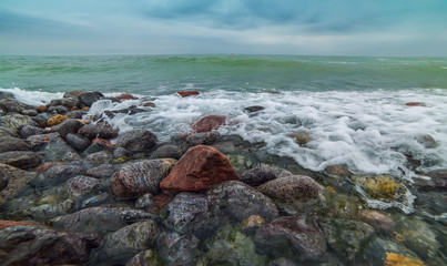 Obraz premium different stones on the beach, the oncoming wave. beautiful sea view. 
