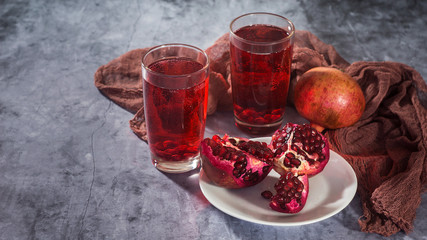 Ripe pomegranates with juice on a gray stone table