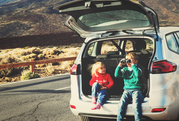little boy and girl looking through binoculars travel by car