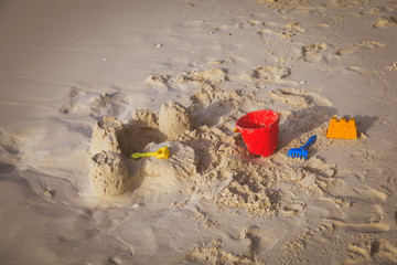Fototapeta na wymiar Sand castle on tropical beach and kids toys