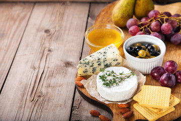 Cheese, honey and fruit on a table. Selective focus.  Copy space.