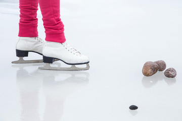 Woman skating with white skates on the ice area at the seashore in winter day. Weekends activities outdoor in cold weather.