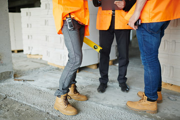 Low section shot of legs of two construction workers wearing jeans and brown leather work boots...