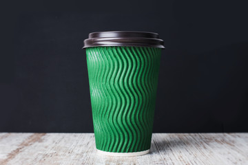 Green paper cup of coffee or tea on a black background