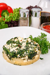 Pie with spinach and cheese decorated with parsley and lettuce on a white plate